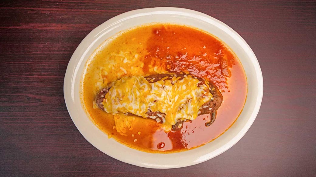 A roasted poblano pepper stuffed with cheese, covered in a rich red sauce and melted cheese.